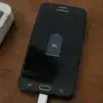 Android phone plugged into charger not charging showing 0 percent battery on screen.
