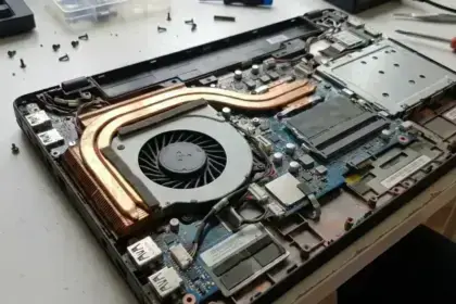 Why is My Laptop Fan So Loud image - a disassembled laptop chassis showing thick dust accumulation blocking the copper heatsink fins and cooling fan blades.